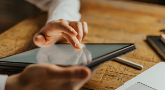Close up photo of male hands tapping on digital tablet screen.