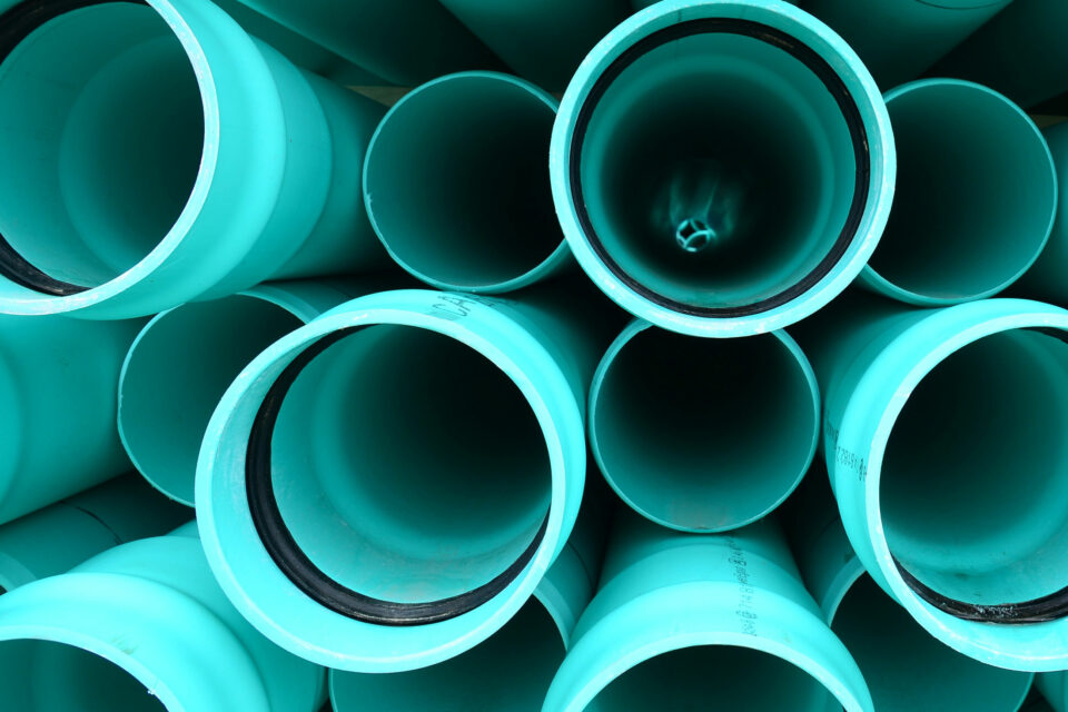 Mint-colored PVC pipes (polyvinyl chloride) stacked from the front so that you can look inside the pipes.